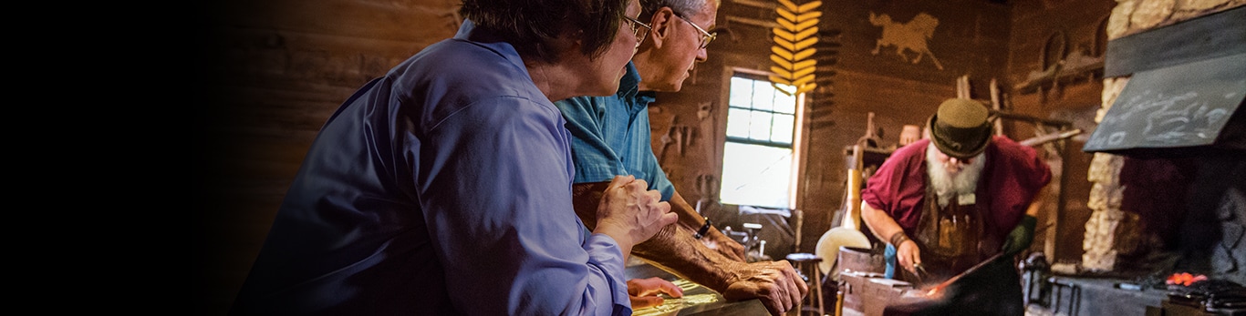 คู่รักสูงวัยกำลังมองดูค้อน Blacksmith ซึ่งเป็นเป็นค้อนโลหะอันหนึ่ง ณ โบราณสถานในเมืองแกรนด์ดีทัวร์ รัฐอิลลินอยส์ ประเทศสหรัฐอเมริกา